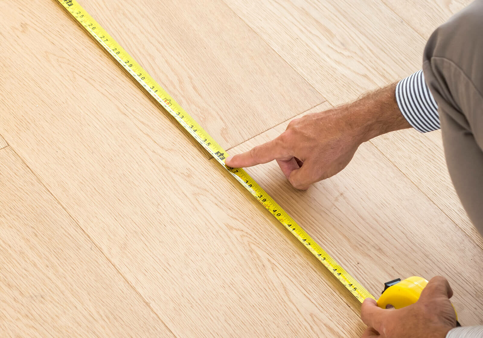 Man measuring laminate floor | Carpetland USA